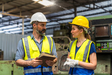 Factory Manager And Worker. Young Man And Young Woman Are Discussing In Industrial Plants. Engineer With Clipboard And Tablet On Hand To See How The Machine Works.