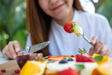 Closeup of a young woman eating mixed fruits french toast brunch in restaurant