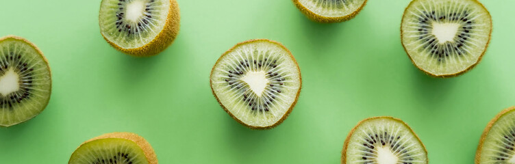 Wall Mural - flat lay of juicy fresh kiwi fruit on green, banner.