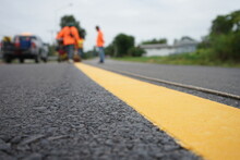 Blurred image of yellow traffic marking work on paved road