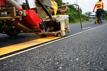 Blurred image of yellow traffic marking work on paved road