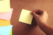 colorful post it paste on brown wood background have copy space for put text to do list and hand of people need to push or pull yellow post it out from wood board. Vintage tone.