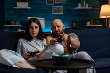 Wall Mural - POV of young couple using console to play videogames challenge, doing online competition on cyberspace. Focused boyfriend and girlfriend playing together to do fun leisure activity.