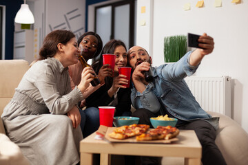 Wall Mural - Business people taking pictures on smartphone at office party with drinks and snacks after work hours. Colleagues using mobile phone to take selfies and make memories at fun celebration.