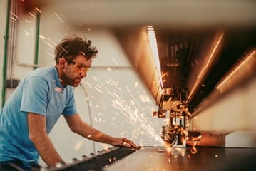 Within heavy industry. A man works in a modern factory on a CNC machine. Selective focus