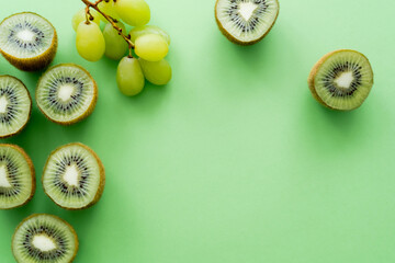 Canvas Print - top view of kiwi fruit near grapes on green.