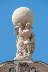 Old statue of powerful Heracles aka Atlas of Renaissance Era holding a globe, Earth at his shoulders in Dresden historical downtown at blue sky background, Germany.