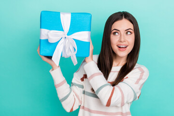 Wall Mural - Photo of adorable excited woman wear striped sweater guessing inside gift box isolated turquoise color background