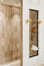 Beige Tiled Wall In Contemporary Bathroom Decorated With Vase And Rolled Towels
