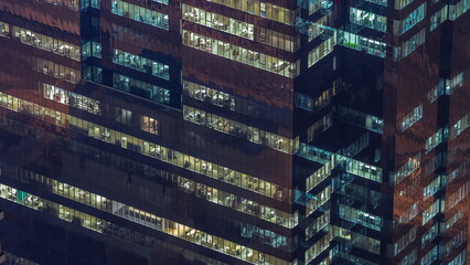 Wall Mural - Windows in office building exterior in the late evening with interior lights on timelapse