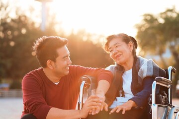 Portrait of smiling young Asian man enjoying sweet tender time outdoor with older senior mother.