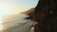 Aerial Of Sunset Ocean Landscape Of Madeira Island, Portugal. Sun Set Light Mountain Rock Cliffs Over Sea Shore And Amazing Waterfall Falling Into Ocean. Drone View Beautiful Travel Destination