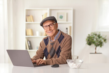 Poster - Smiling elderly man sitting at home and using a laptop