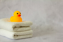 A Yellow Rubber Duck For Bathing On A Stack Of Clean White Towels.