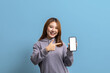 © kamiphotos - Portrait of beautiful Asian woman holding mobile phone on isolated background, portrait concept used for advertisement and signage, isolated over blue background, copy space.