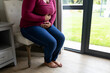 © Wavebreak Media - Low section of african american mid adult woman suffering from stomachache while sitting on chair