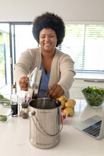 Smiling African American Mid Adult Woman Putting Waste In Garbage Bin While Preparing Food