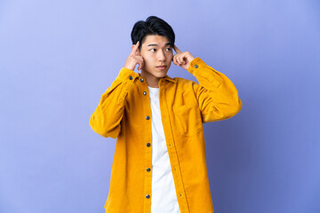 Wall Mural - Young Chinese man isolated on purple background having doubts and thinking