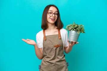 Wall Mural - Gardener Ukrainian woman holding a plant isolated on blue background with shocked facial expression