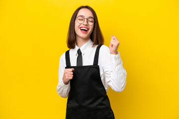 Wall Mural - Young Ukrainian waitress woman isolated on yellow background celebrating a victory