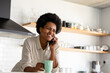 © Wavebreak Media - Smiling mid adult african american woman talking on smart phone while having coffee in kitchen