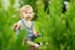 © MNStudio - Silly toddler boy putting grass and soil in his mouth while playing outdoors on sunny summer day. Curious child exploring nature.