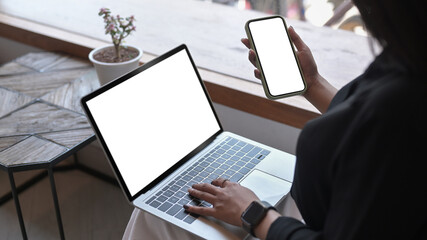 Wall Mural - Young woman working with computer laptop and using mobile phone at cafe.