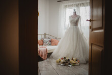 Beautiful Wedding Gown In The Room On The Mannequin With Shoes And Flowers.