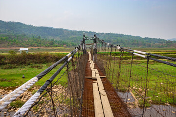 isolated iron suspension bridge old with misty mountain background at morning