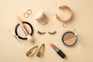 Wall Mural - Make up concept. Top view photo of circle composition false eyelashes lipstick compact powder brush contouring palette eyeshadow gold wristlet rings and barrettes on pastel beige background