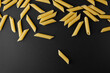 Raw pasta penne rigate with copy space on black background.