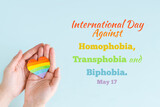 Fototapeta Kawa jest smaczna - Concept International Day Against Homophobia, Transphobia and Biphobia. May 17. Stop Homophobia. Heart with rainbow LGBT flag in hands on blue background.