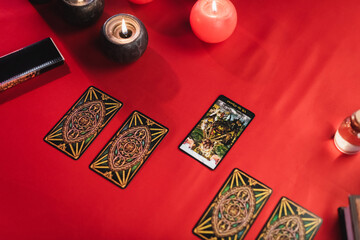 Poster - KYIV, UKRAINE - FEBRUARY 23, 2022: Top view of tarot cards near burning candles on table.