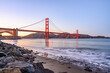 Beautiful view of the Golden Gate Bridge in California, USA by the rocky beach with sunset sky