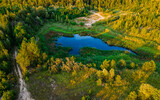 Fototapeta Łazienka - Aerial view of a small lake in the middle of the forest and near a forest road