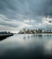 Poster - Boston skyline along the harbor against cloudy sky across the Atlantic ocean, Massachusetts, USA