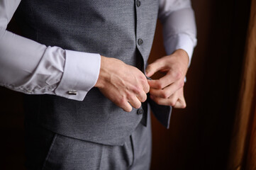 A man fastens a button on his jacket, close-up.Morning preparation of the groom.