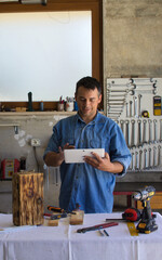 Wall Mural - Man with a passion for DIY checks projects with his tablet in his workshop.