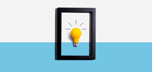 Wall Mural - Yellow light bulb inside a frame - inspiration, creativity, energy, electricity themes