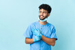 © luismolinero - Moroccan dentist man holding tools isolated on blue background looking up while smiling