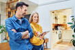 © baranq - Happy middle aged couple standing at home with digital tablet talking
