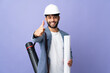 © luismolinero - Young architect Moroccan man with helmet and holding blueprints over isolated background with thumbs up because something good has happened