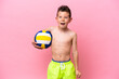 Little caucasian boy playing volleyball isolated on pink background with surprise and shocked facial expression