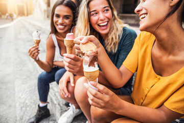 Laughing teenage girls eating ice cream cones on city street - Young female friends enjoying icecream outside - Summer lifestyle concept