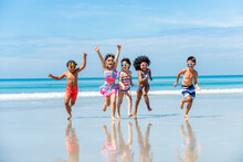 Group Of Diversity Little Child Boy And Girl Friends Running And Playing In Sea Water On Tropical Beach Together On Summer Vacation. Happy Children Kid Enjoy And Fun Outdoor Lifestyle On Beach Holiday