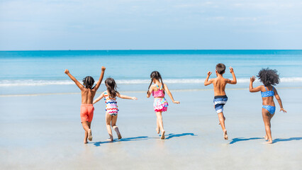 Wall Mural - Group of Diversity little child boy and girl friends running and playing in sea water on tropical beach together on summer vacation. Happy children kid enjoy and fun outdoor lifestyle on beach holiday