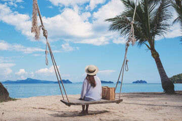 Rear view image of a young woman sitting on wooden swing by the sea