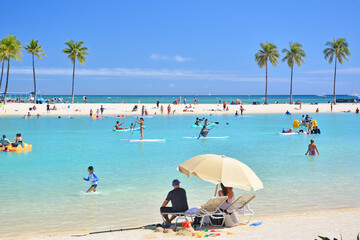 Tourists enjoying the warm sunny weather at Duke Kahanamoku Lagoon in Waikiki Beach, Honolulu on Oahu, Hawaii