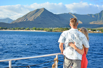 couple on vacation enjoying mountain and ocean views from a tour boat on oahu, hawaii
