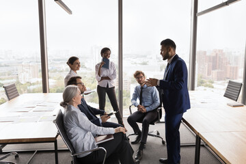 Wall Mural - Happy engaged Indian business leader motivating diverse staff for work, brainstorming, sharing ideas for project. Mentor, coach, teacher training group of millennial interns, employees